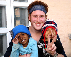 A young man and two children hold up the peace sign while smiling