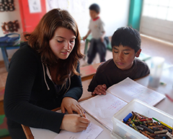 Female volunteer assisting young boy with his homework