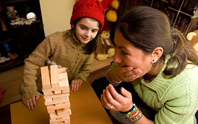 Female volunteer playing Jenga with young romanian child