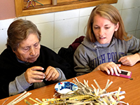 Female volunteer helps elderly woman with crafts