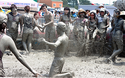Group of Korean teenagers play in a pool of mud during the Boryeong Mud Festival, South Korea
