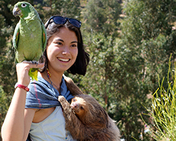 Female volunteer poses with sloth in Peru