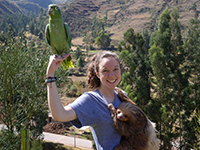 Volunteer poses with sloth and parrot 