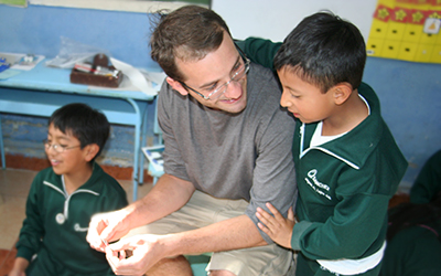 Male volunteer teaching young Ecuadorian child
