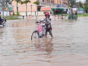A lady and a bike and a lot of water in Cambodia