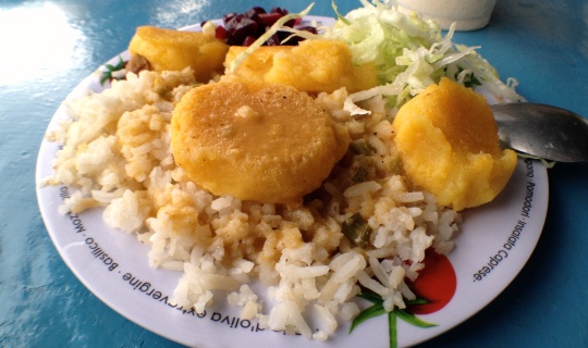 A plate of Llapingachos on top of white rice and lettuce.