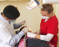 Two dental students perform oral surgery on a child.