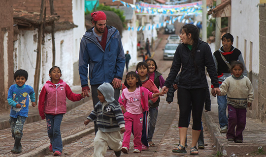 Volunteers walk towards camera holding hands with young children